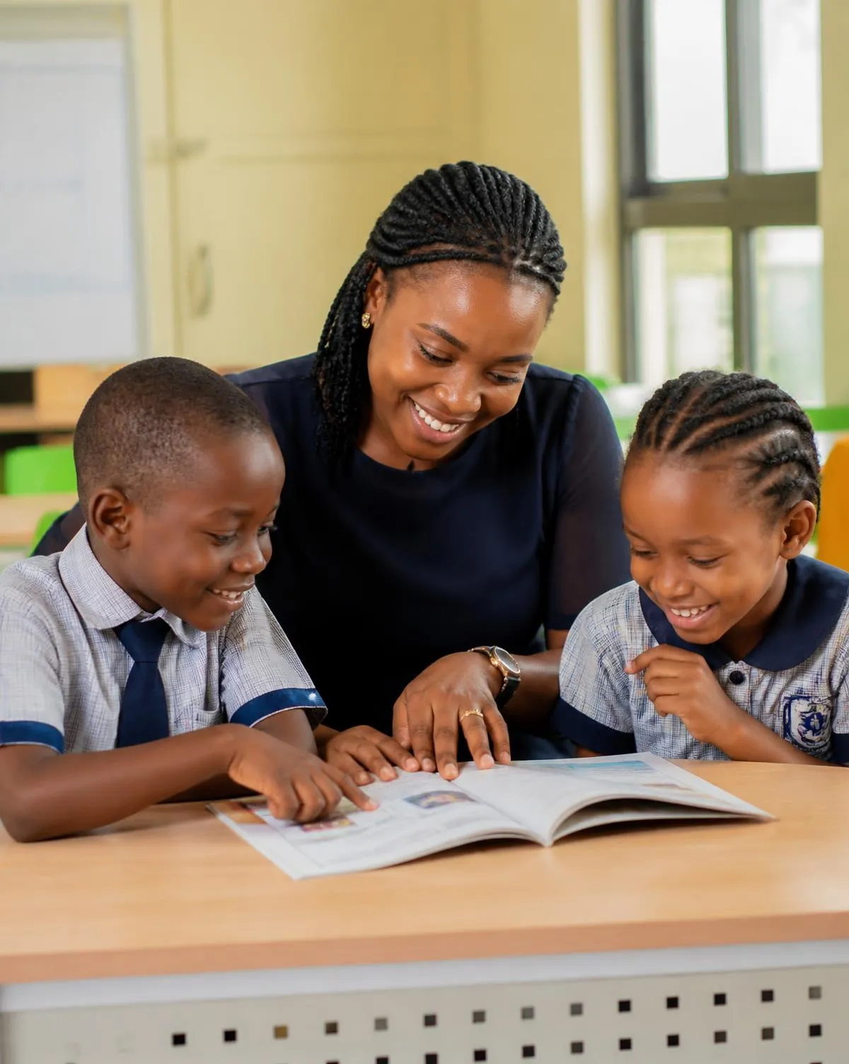 A teacher reading with two Key Special Academy pupils in a bright classroom